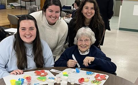 Three female students pose with a resident of Portland's Barron Center, a long-term care facility